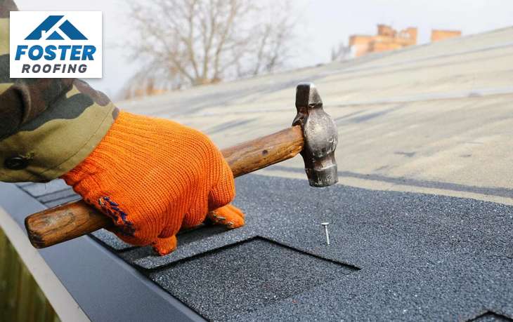 Roofer hammering nails to install roof shingles